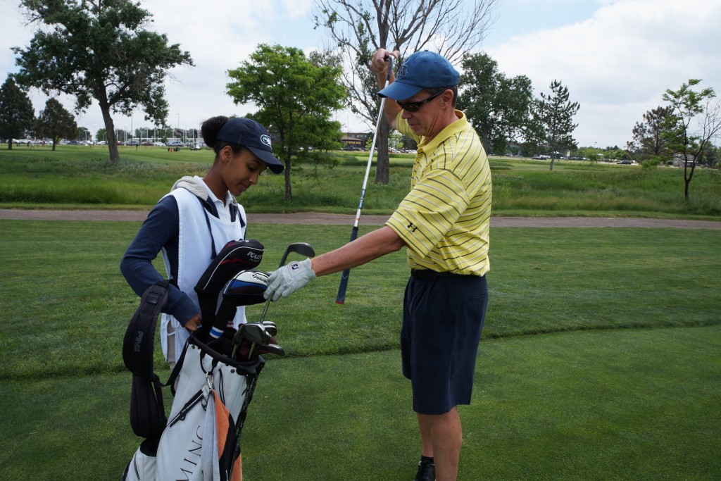 Helena Seyoum hands off a new club to golfer Mark Brorby. Photos by Katherine Blunt.