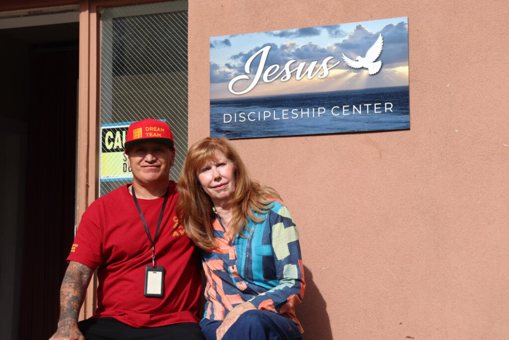 Camille Curry sitting outside the Jesus Discipleship Center with a volunteer.