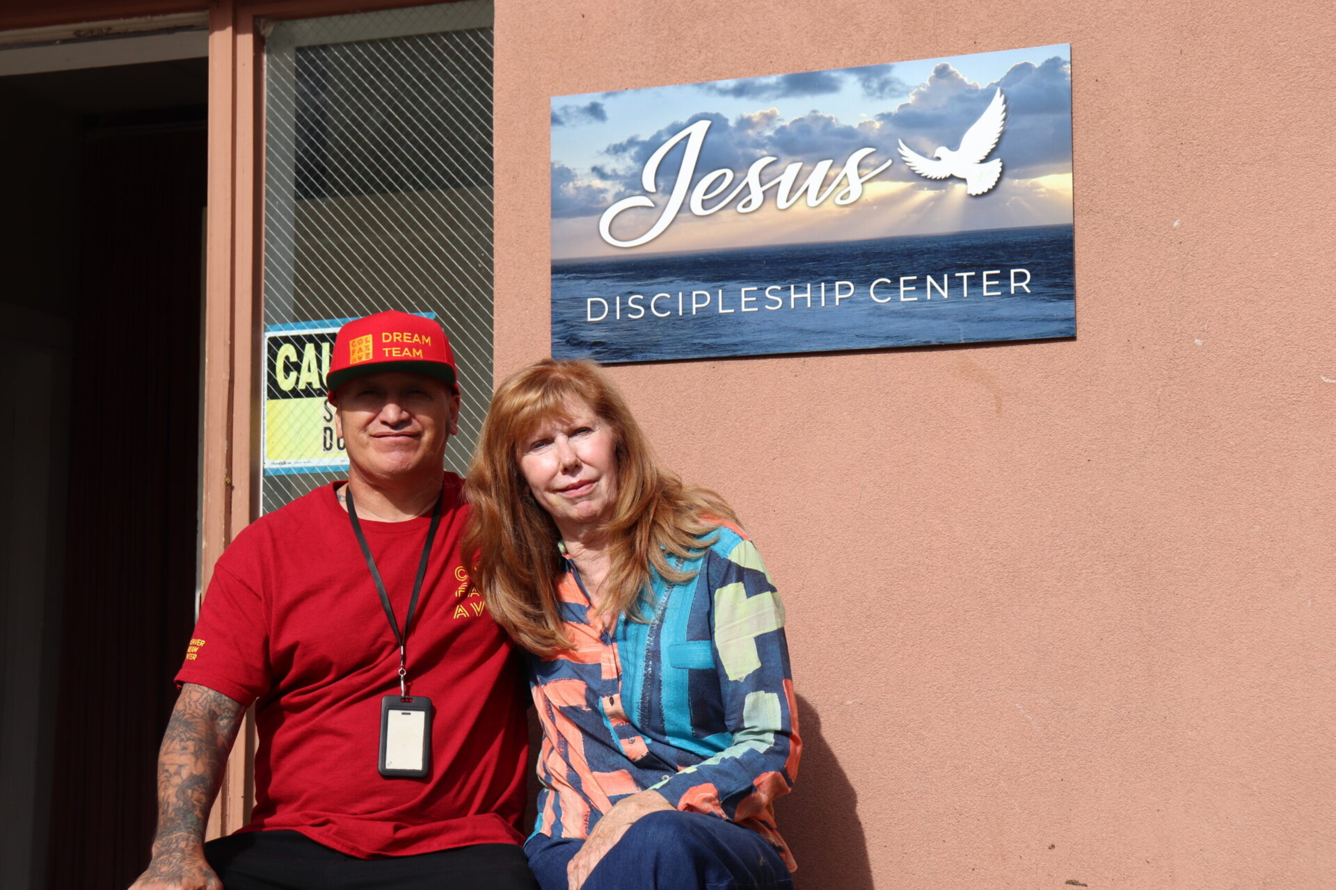 Camille Curry sitting outside the Jesus Discipleship Center with a volunteer.