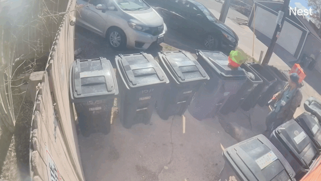 An apparent homeless person with a knife rummages though trash bins across from the center. 
