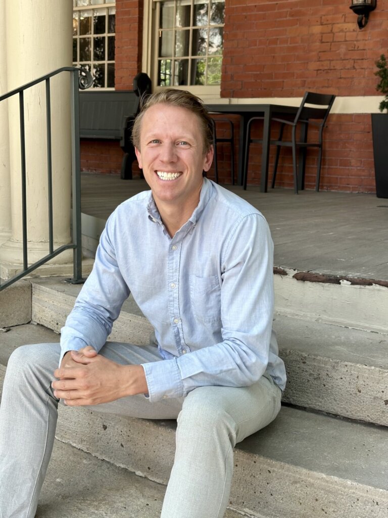John Goshca sitting down in front of The Carriage House.