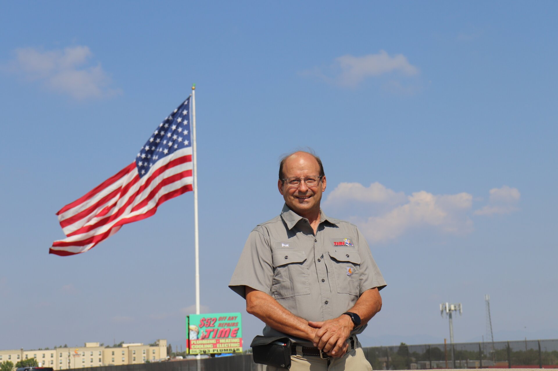 Brad Apple stands in front of giant 6th Avenue flag