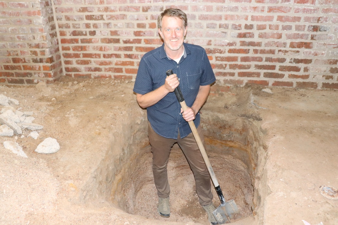 Matt Van Sistine inside the basement of 2100 Larimer holding a shovel.
